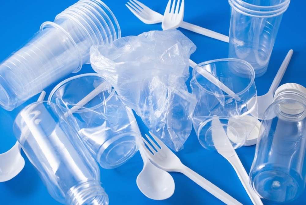 Picture of plastic cutlery, cups and bags on a blue background