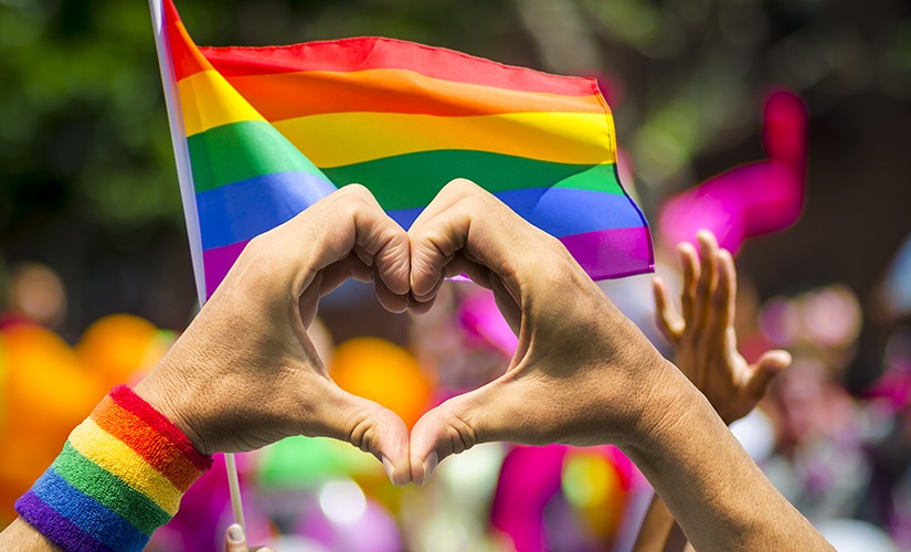 A picture of a person making a love gesture with his hands at a Pride parade