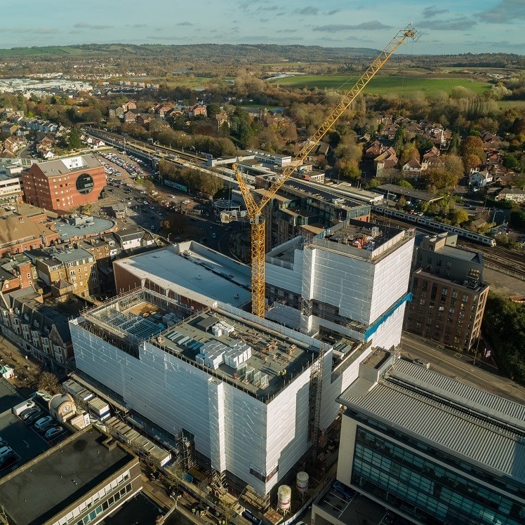 Picture from a drone of the Marketfield Way development. White buildings and a crane, views behind of trees and green fields
