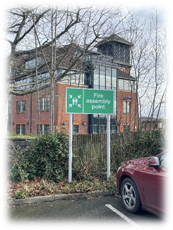 Assembly point sign on a pole in south east corner of the Town Hall car park.