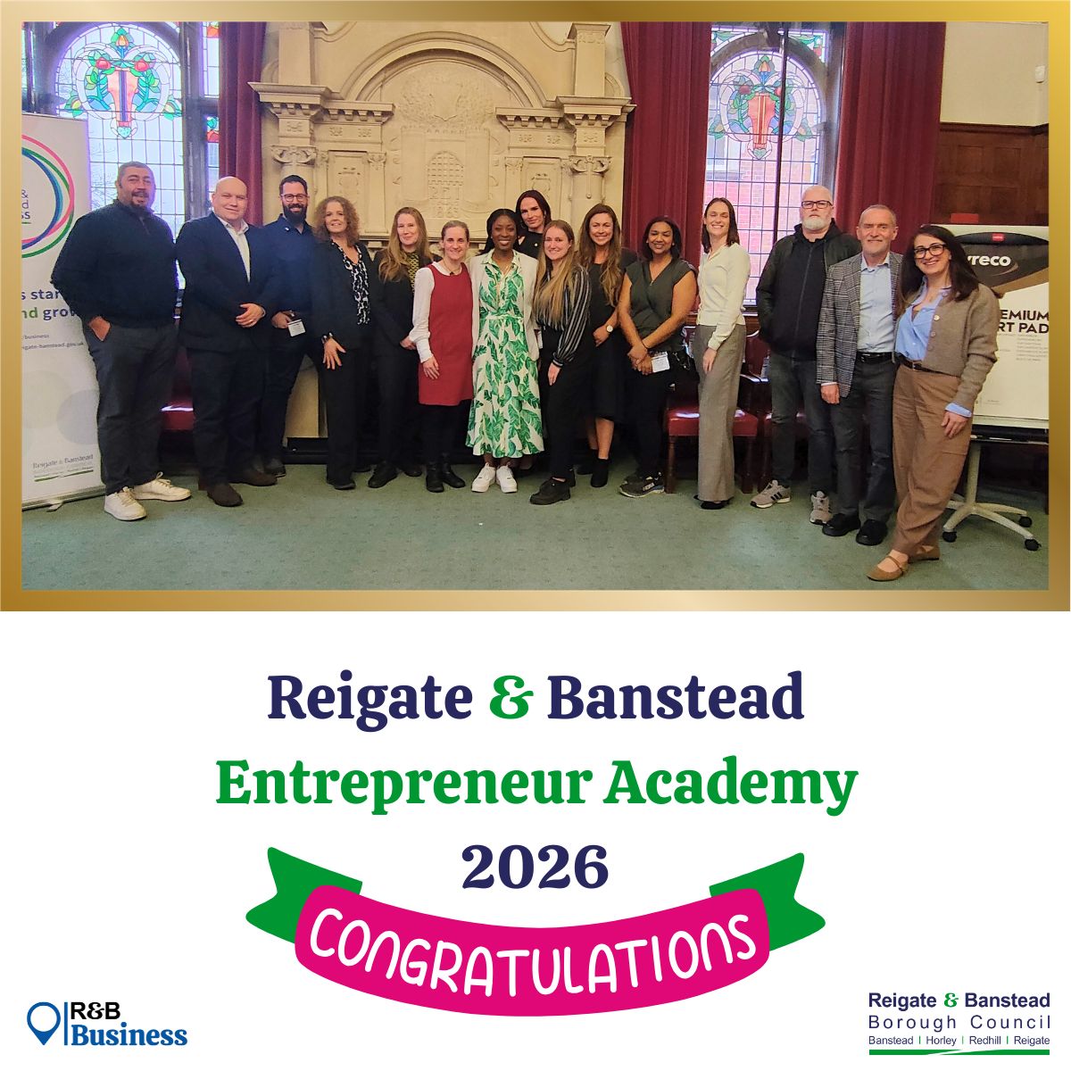 A group of people standing together in a formal room with stained‑glass windows and decorative architectural details, posing for a graduation-style photo. Beneath the image is the text ‘Reigate & Banstead Entrepreneur Academy 2026’ with a ribbon graphic that reads ‘Congratulations.’ Logos for R&B Business and Reigate & Banstead Borough Council appear at the bottom.