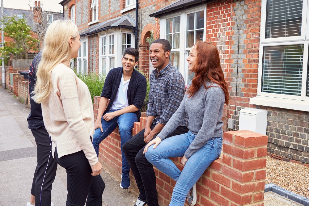 Group of young adults talking together outside a home