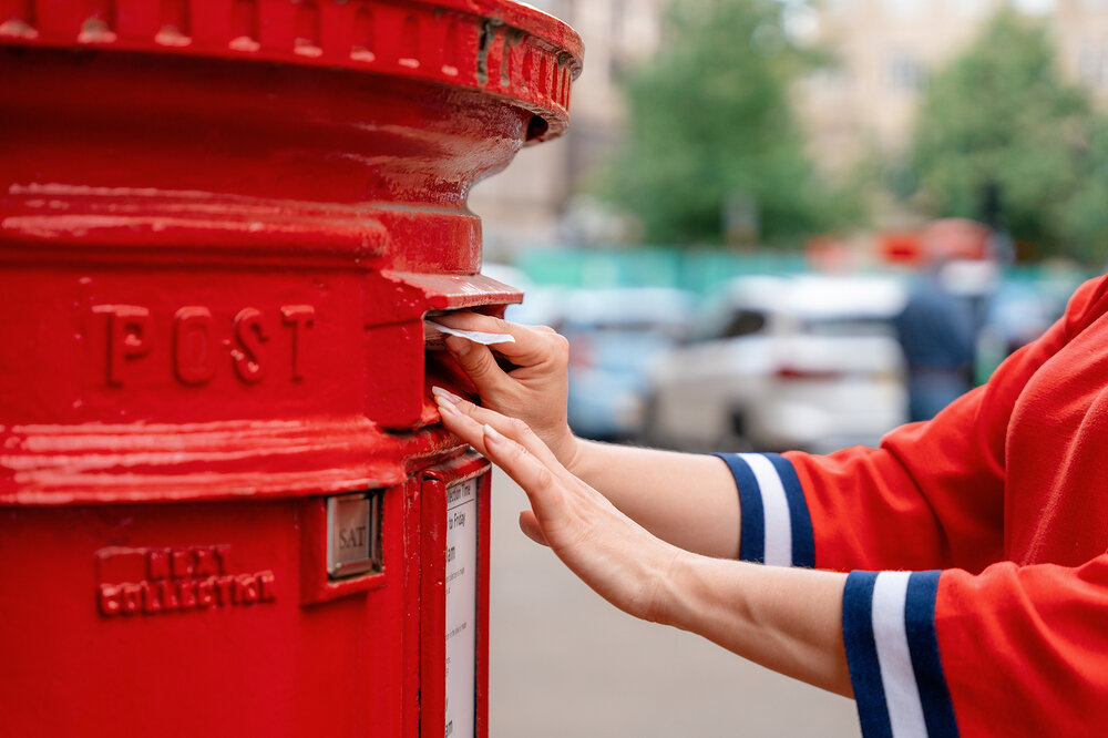 Person putting a postal vote into a postbox