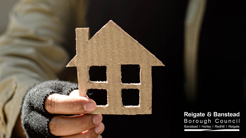 Person holding a cardboard cut-out of a house