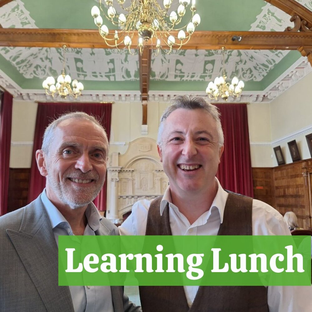 Two smiling men with gray hair in the Old Council Chamber
