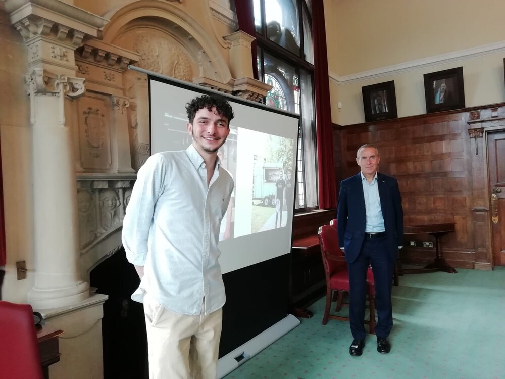 Picture of two men smiling infront of a a projector screen at the Learning Lunch