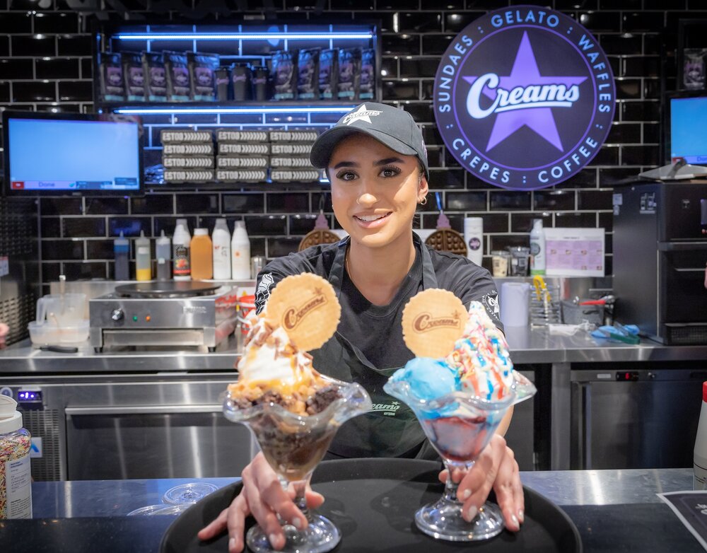 A Creams team member with two ice cream sundaes