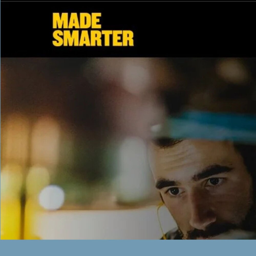 Graphic with the words ‘Made Smarter’ in bold yellow text at the top, set against a blurred background with warm, out‑of‑focus lights