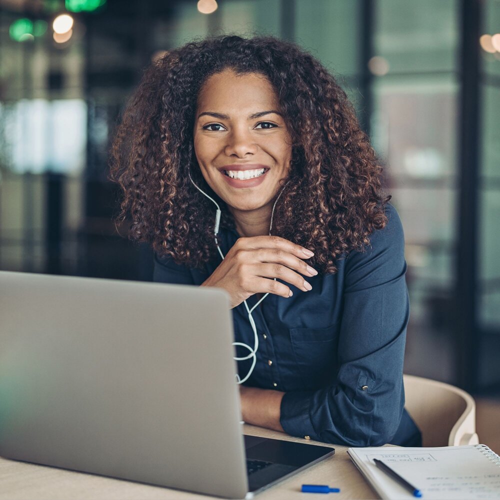 Woman sitting in front of laptop wearing headphones