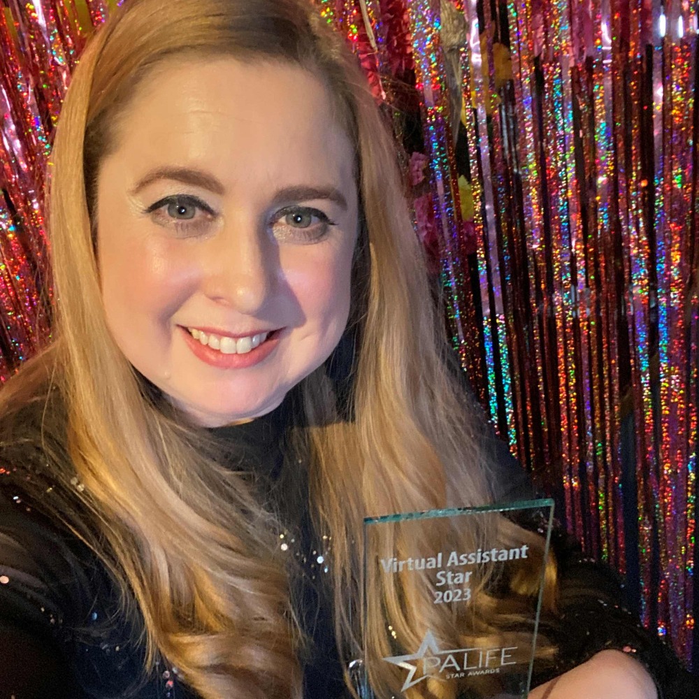 Smiling blonde lady with glass award infront of pink glittery backdrop